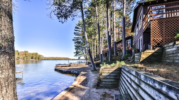 A lakeside cabin with a dock, wooden steps, and a deck overlooking the water.