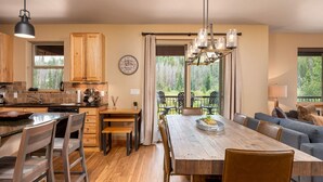 A modern kitchen with wooden cabinets, a large island, and a dining area with a wooden table and chairs.