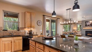 A spacious kitchen with wooden cabinets, a granite countertop, and pendant lighting.