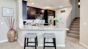 Uma cozinha moderna com armários de madeira escura, eletrodomésticos de aço inoxidável e uma ilha central com banquetas.