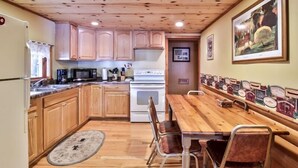 Una cocina con armarios de madera, estufa, microondas y una mesa de comedor con sillas.