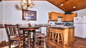 A rustic kitchen with wooden cabinets, a central island with stools, and a dining area with mismatched chairs.