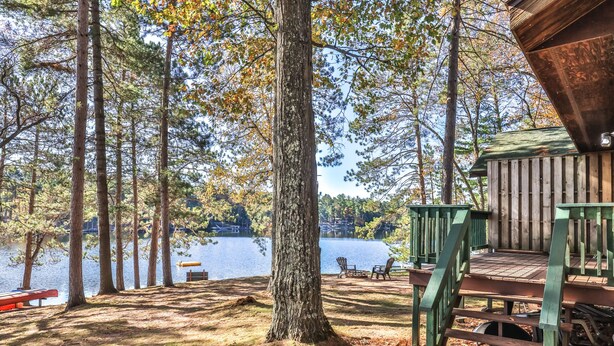 A rustic wooden deck with a view of a lake and trees.