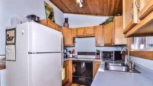 A modern kitchen with wooden cabinets, a white refrigerator, a stove, a microwave, and a sink.