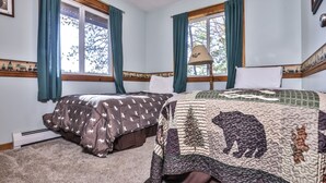 A bedroom with two beds, a window with curtains, a lamp, and a radiator.