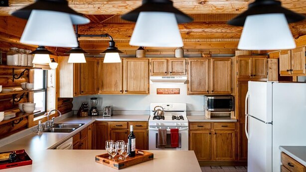 Una cocina con armarios de madera, estufa, microondas y lámparas colgantes.