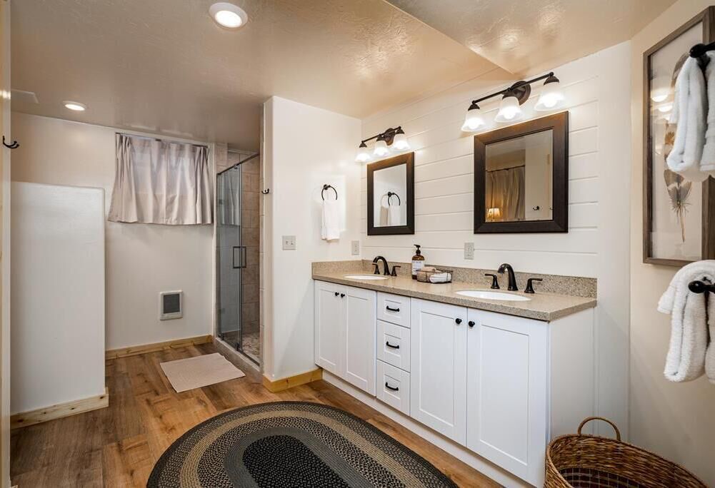 A modern bathroom with a double sink, vanity, and a shower area.