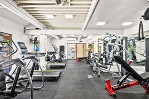 A gym with treadmills, elliptical machines, and weightlifting equipment. - Kamaole Sands 9-301 - Luxurious Renovation, Split AC, Wi-Fi, Ocean View Condo (Kihei)