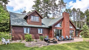 A log cabin with a large deck, outdoor seating, and a chimney.