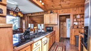 Eine Holzhütte mit einer Kücheninsel, Holzschränken, einer Mikrowelle und einem Kühlschrank.