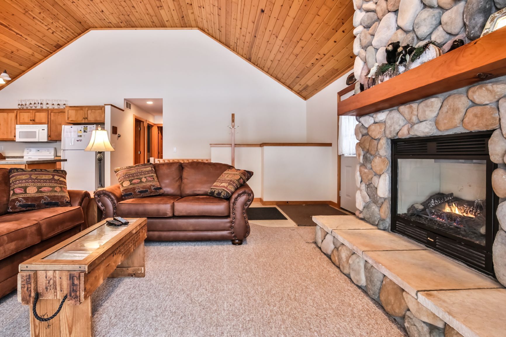 A cozy living room with a stone fireplace, leather sofa, and a wooden coffee table.