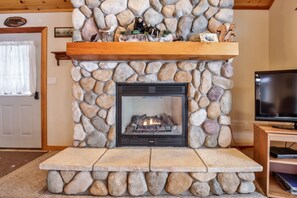 A stone fireplace with a TV on a wooden stand to the right.