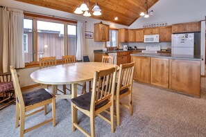 A cozy kitchen with wooden cabinets, a round dining table, and a breakfast bar.