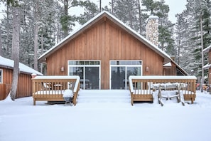 A wooden cabin with a large sliding glass door, surrounded by snow-covered trees.
