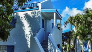 A modern building with a blue roof and white walls, featuring a set of stairs leading to a covered entrance.