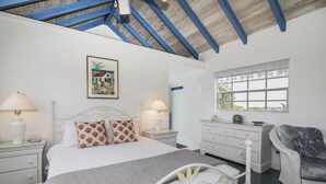 A bedroom with a bed, bedside tables, a dresser, a chair, and a window with a view.
