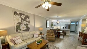 A spacious living room with a sofa, armchairs, a coffee table, and a dining area with a chandelier. - RI 410 Huge Double Shower! Beach Front! Popular Unit! Kitchen & Bath Upgrades (Orange Beach)