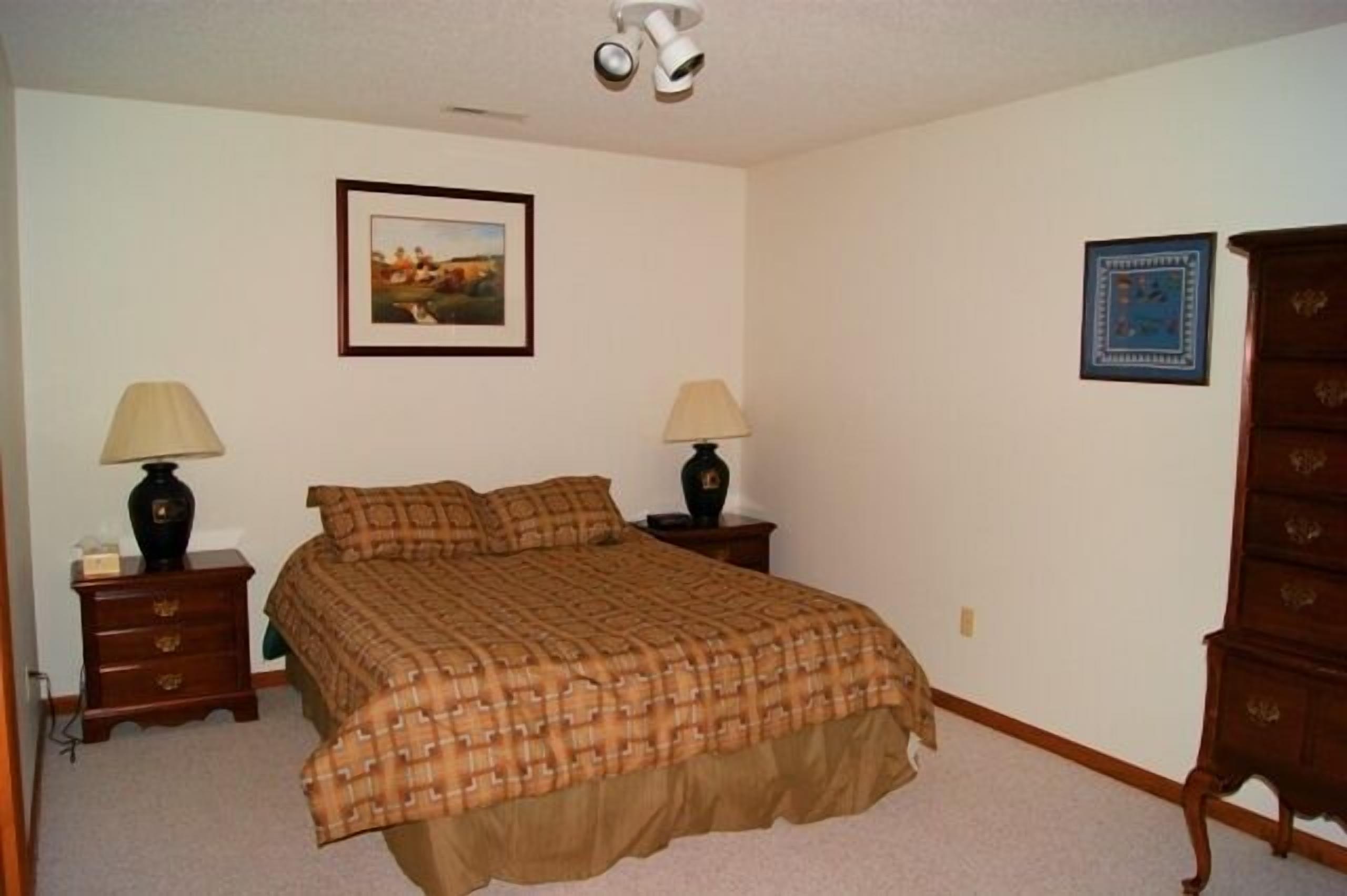 A bedroom with a bed, two nightstands, a dresser, and two lamps.