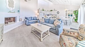 Ein Wohnzimmer mit Sofa, Couchtisch, Kamin und Essecke mit Stühlen und Tisch.