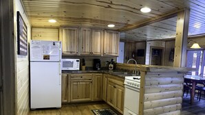Une cuisine de style rustique, avec des meubles en bois, un réfrigérateur, un four à micro-ondes et une cuisinière.