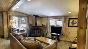Un salon chaleureux avec un canapé en cuir, une cheminée, un téléviseur et une table basse en bois.