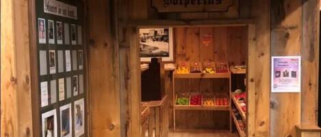 Una vetrina in legno con un'insegna che recita "General Store" e "Wolverines". C'è una panchina fuori e scaffali pieni di diversi articoli all'interno.