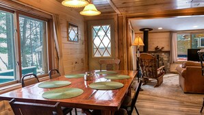 Un coin repas en bois avec une grande table, des chaises et deux lampes suspendues.