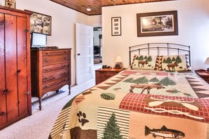 Un dormitorio con una cama grande, un aparador de madera, un escritorio y un cuadro en la pared.