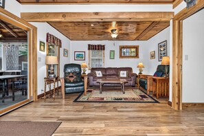 Uma sala de estar aconchegante com teto de madeira, poltrona de couro, sofá marrom e mesa de centro.