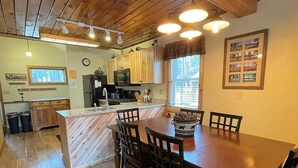 Une cuisine avec des meubles de rangement en bois, un îlot central et un coin repas avec des chaises.