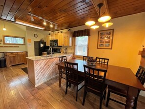 Una cocina con armarios de madera, una isla central con un lavamanos y un comedor con mesa y sillas.