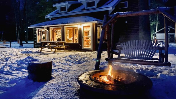 A cabin with a fire pit and a covered seating area. - Lakefront cabin on Lost Lake with dock and firepit next to bar and grill! (St. Germain)