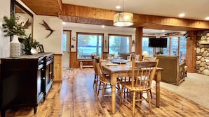 A wooden dining area with a large table and chairs, a fireplace, and a stone wall. - Lakefront cabin on Lost Lake with dock and firepit next to bar and grill! (St. Germain)