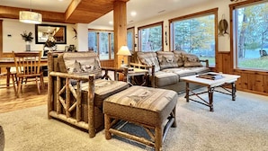 A cozy living room with a wooden ceiling, large windows, and rustic furniture. - Lakefront cabin on Lost Lake with dock and firepit next to bar and grill! (St. Germain)