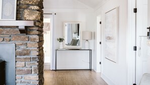 Ein modernes Interieur mit Kamin aus Stein, Holzboden, weißer Wand und einem gerahmten Bild.