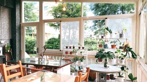 A sunlit room with large windows, a dining table, chairs, and various potted plants. - TONG YI Homestay (Ji'an)