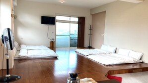 A hotel room with two beds, a TV mounted on the wall, a wooden floor, and a dining table with tea cups and a teapot. - TONG YI Homestay (Ji'an)