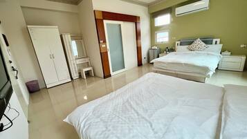 A hotel room with a bed, a desk, a wardrobe, a mirror, and an air conditioning unit.