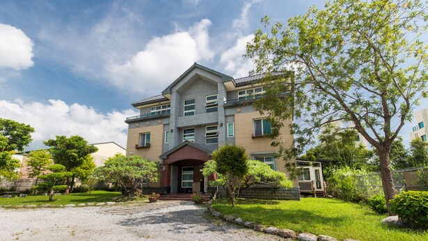 A multi-story residential building with a central entrance, a gravel driveway, and a well-maintained lawn with trees. - TONG YI Homestay (Ji'an)