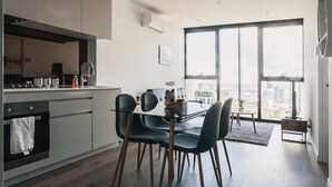 A modern kitchen with a dining area, large windows, and a city view.