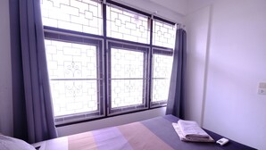 Ein Hotelzimmer mit Bett, Fenster mit Ausblick und Nachttisch mit Fernbedienung.
