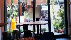 Ein Restaurantinneres mit einer großen Glastür, Tischen, Stühlen und hängenden Lampen.