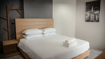 Un dormitorio moderno con estructura de cama de madera, ropa de cama blanca y una cama bien hecha con toallas.