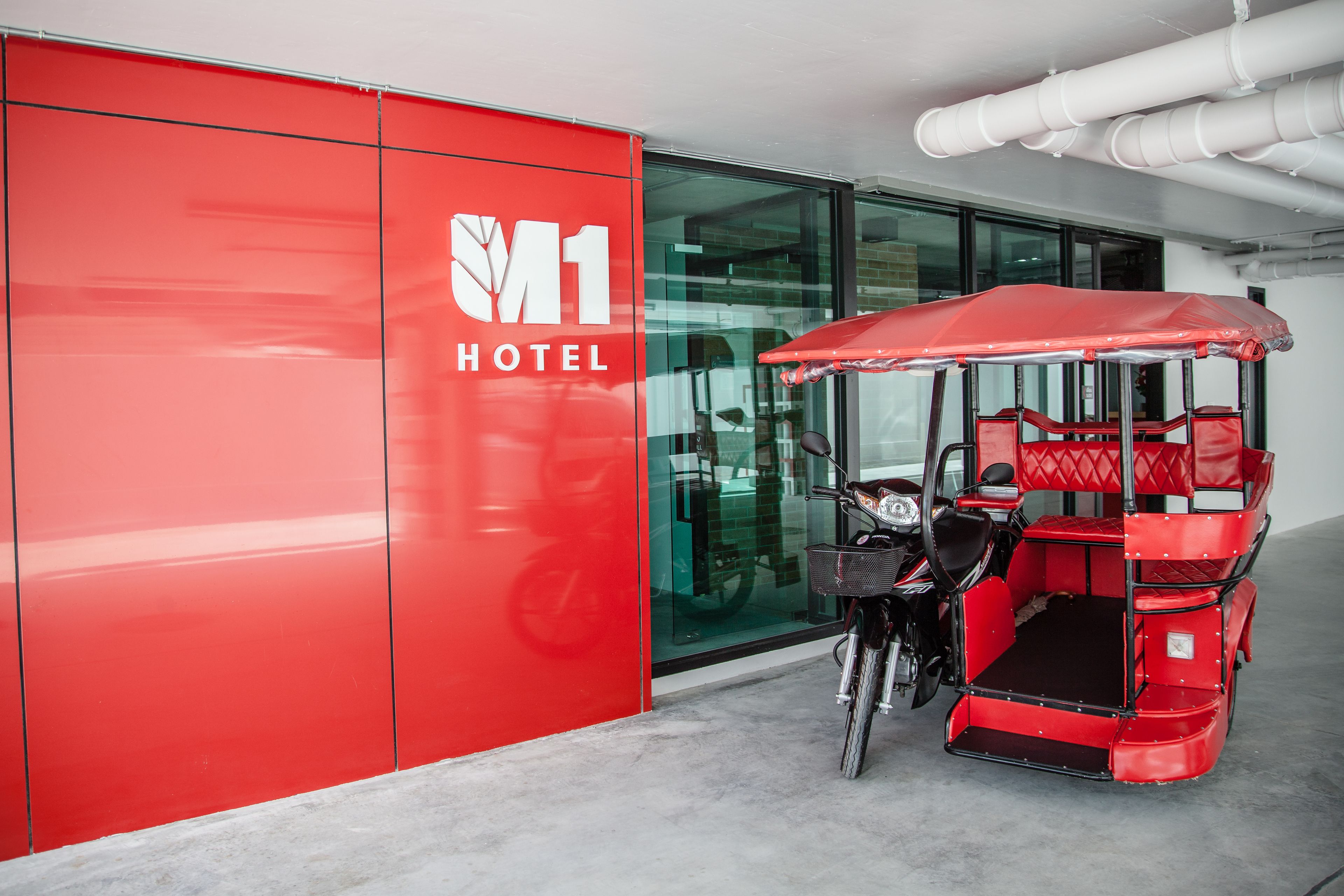 A red M1 Hotel building with a red golf cart parked in front.
