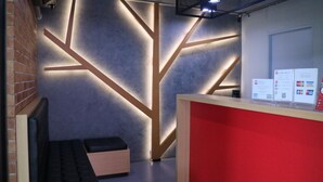 Un espace d’accueil au design moderne, avec un comptoir rouge et un mur orné de motifs géométriques.