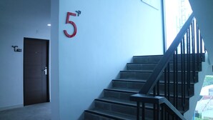 Un escalier avec une rampe en métal, une porte portant l’inscription « 40 », et un grand chiffre rouge « 5 » peint sur le mur.