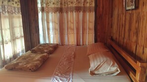 Una habitación con cama, paneles de madera y cortinas de estampado floral.