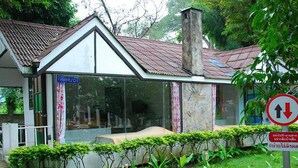Um edifício com fachada de vidro, telhado em telhas e área de jardim com plantas.
