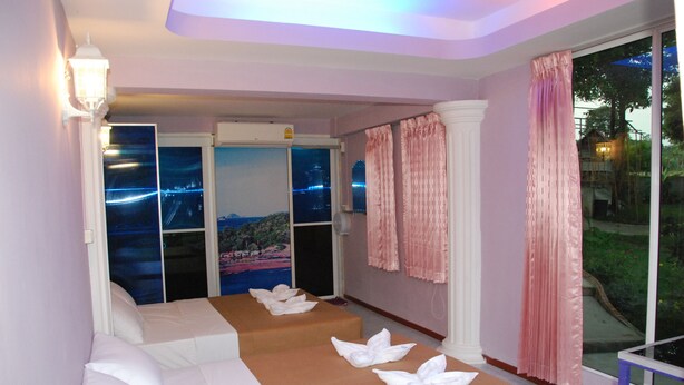 Quarto com duas camas, vista para a cidade e uma grande janela com cortinas.
