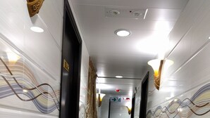 Een gang met een marmeren vloer, witte muren en decoratieve wandpanelen.